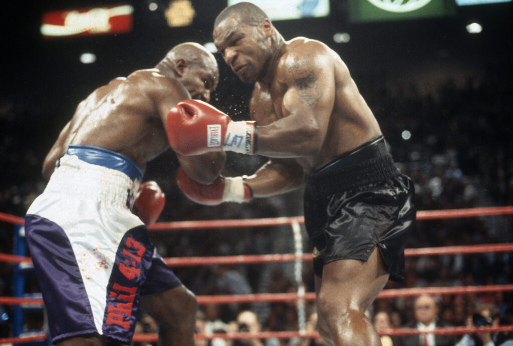 Mike Tyson takes a right hook to the stomach from Evander Holyfield during their 1997 fight