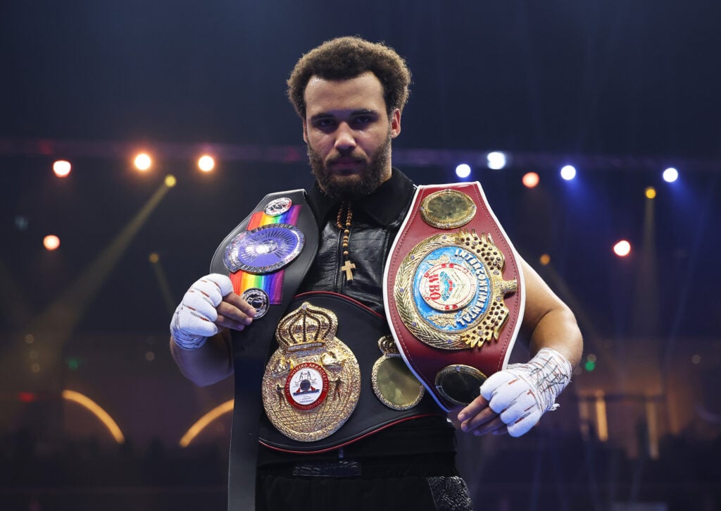 Moses Itauma poses with belts around his waist and over each shoulder