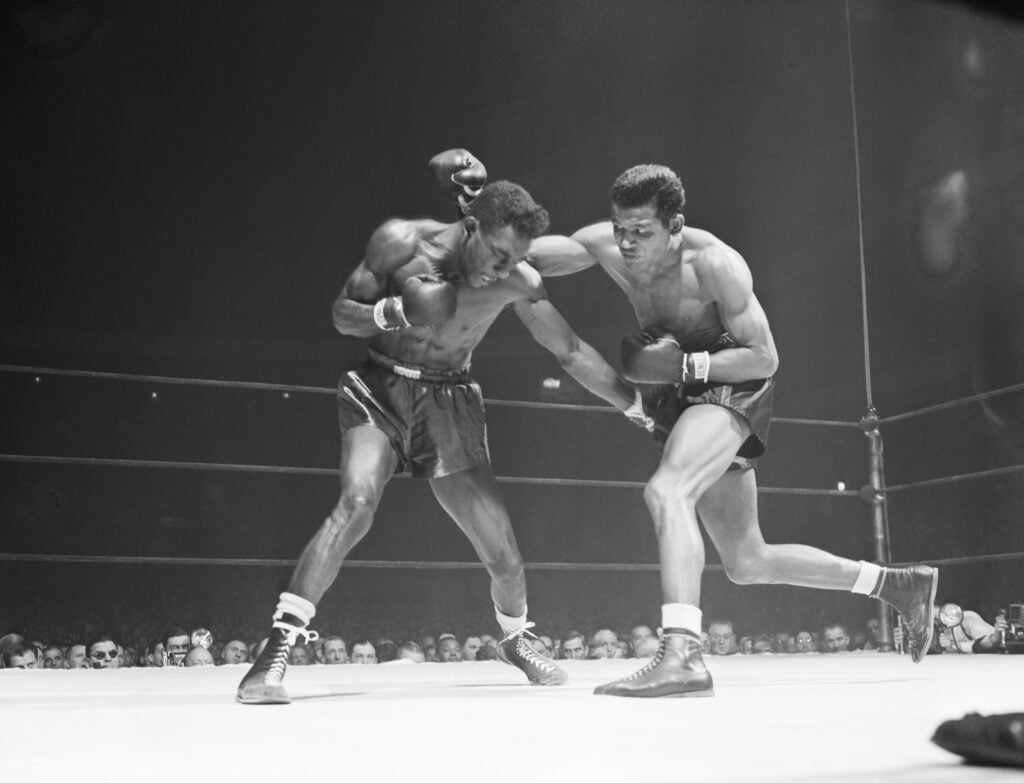 Sugar Ray Robinson Throws right hook in Title Match against Tommy Bell, who ducks to avoid it