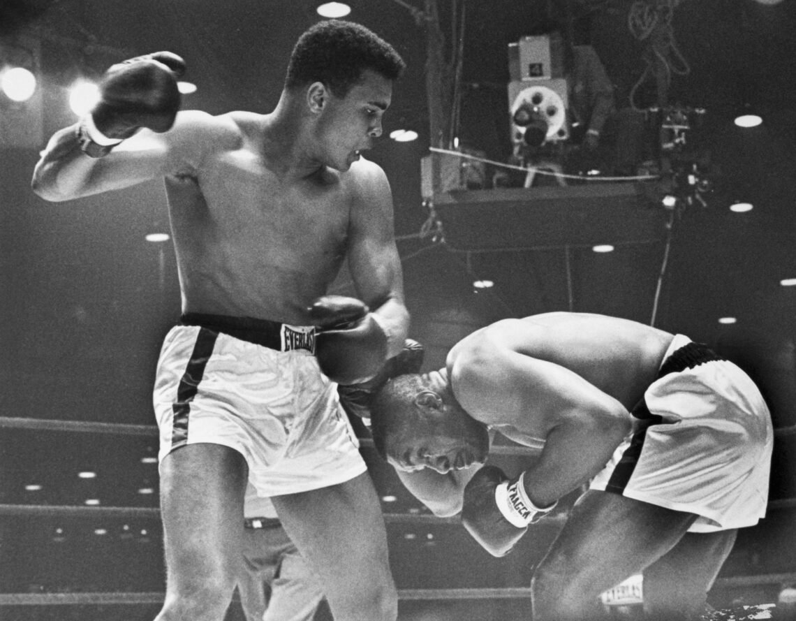 Boxer Sonny Liston ducks and covers up as Cassius Clay (later known as Muhammad Ali) aims a right at him during their title fight. Liston injured h...