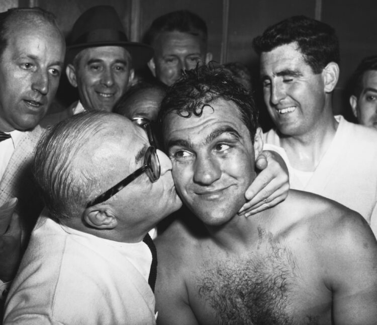 (Original Caption) Heavyweight champion Rocky Marciano gets a kiss from his manager Al Weill in the Yankee Stadium dressing room after the champ's ...