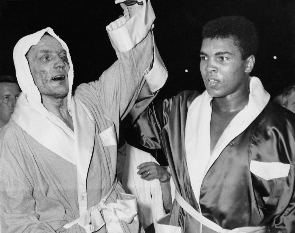 Henry Cooper and Muhammad Ali, then Cassius Clay, raise eachother's hands.