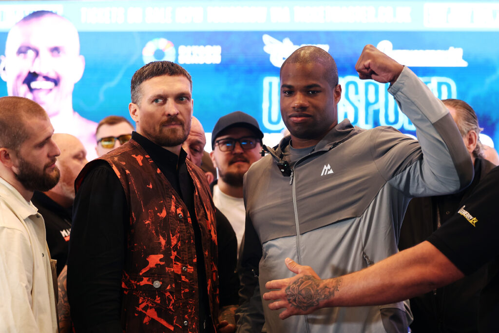 Daniel Dubois raises his fist beside Oleksandr Usyk at their rematch press conference