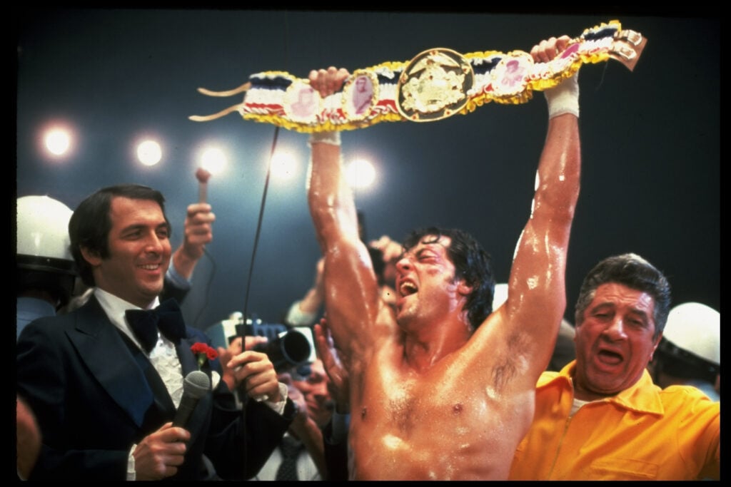 Sylvester Stallone lifts a belt above his head during Rocky V