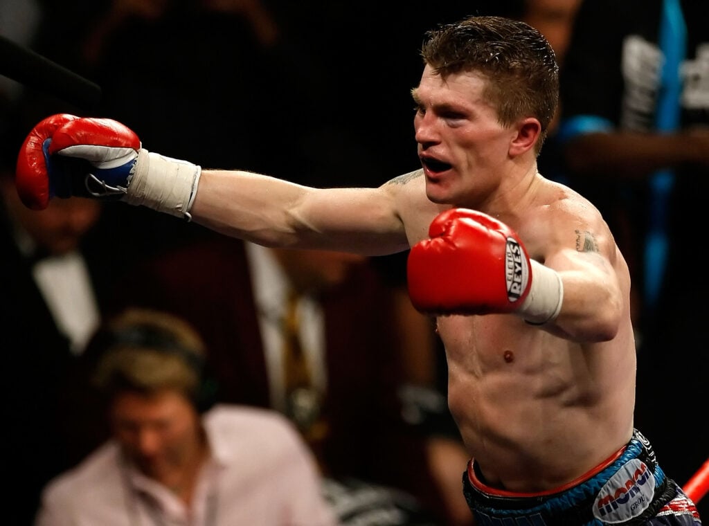 Ricky Hatton celebrates defeating Paulie Malignaggi with his hands in the air as he's stood on the corner ropes