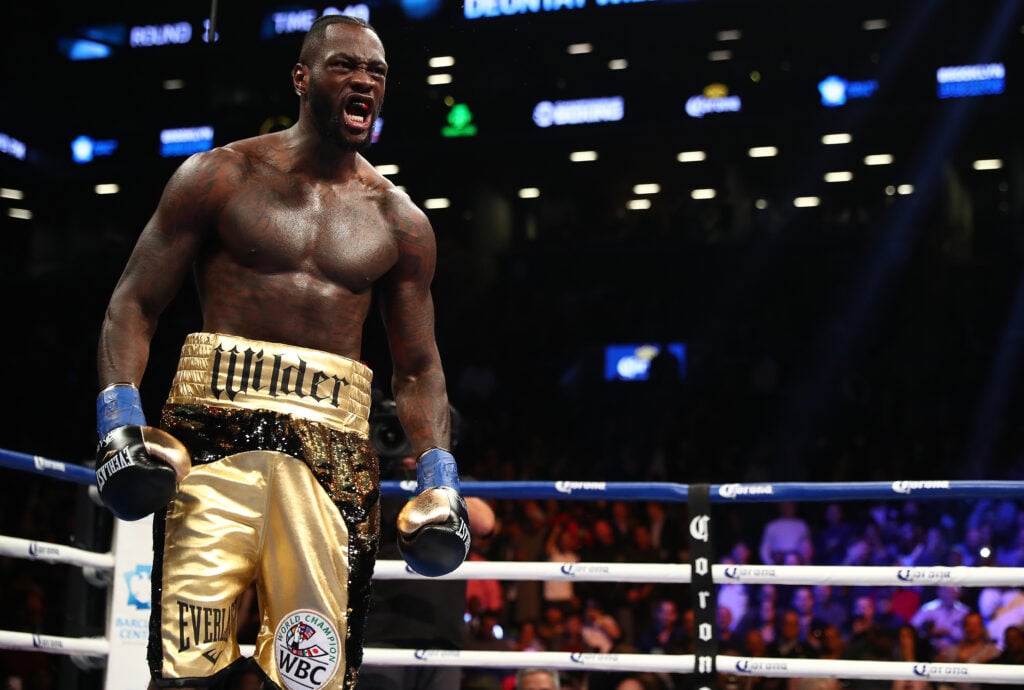 Deontay Wilder celebrates after knocking out Bermane Stiverne in their 2017 rematch, he is wearing black and gold trunks