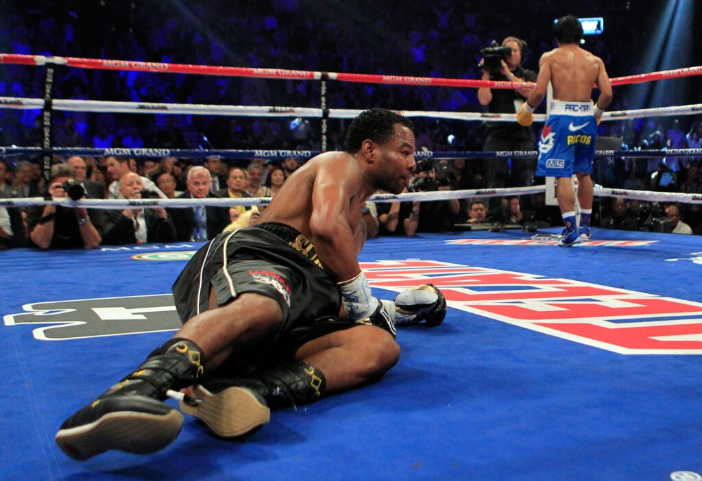 Shane Mosley lies on the canvas as Manny Pacquiao walks away after knocking him down
