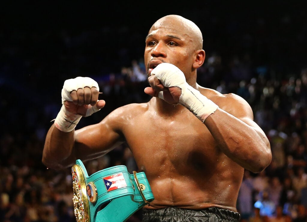 Floyd Mayweather Jr. celebrates defeating Robert Guerrero sitting on ropes with his fists raised