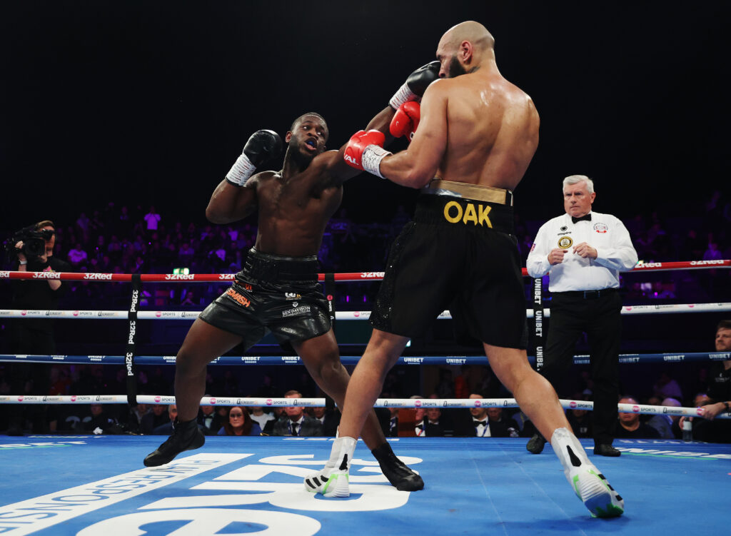 Aloys Jr strikes Lewis Oakford in the head with a straight left