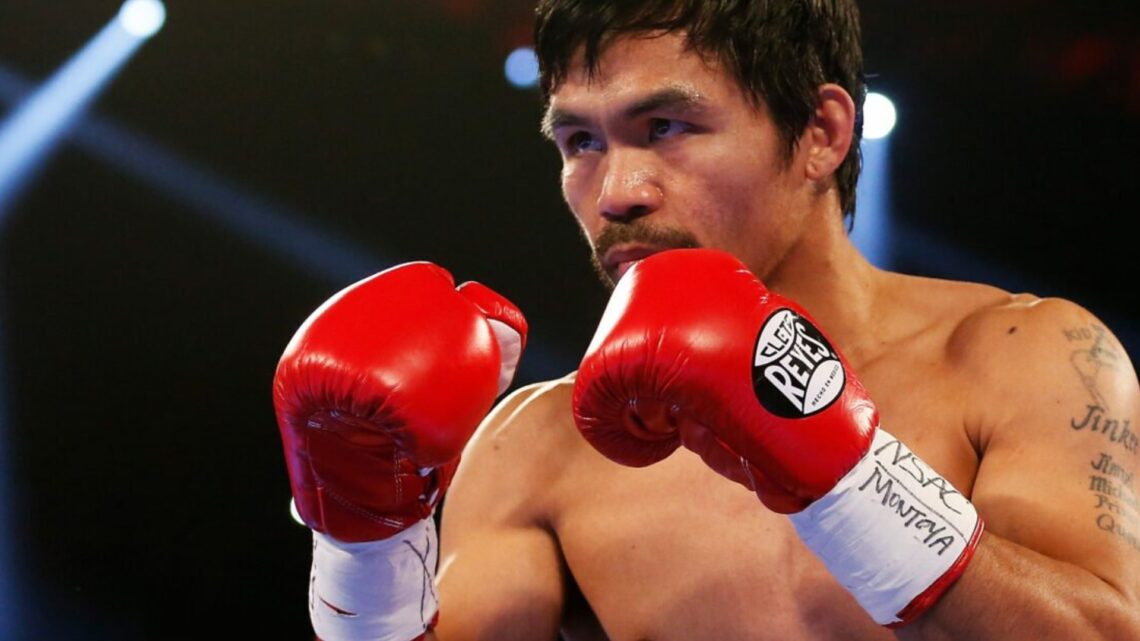 Manny Pacquiao with red gloves on and his hands in high guard during a fight