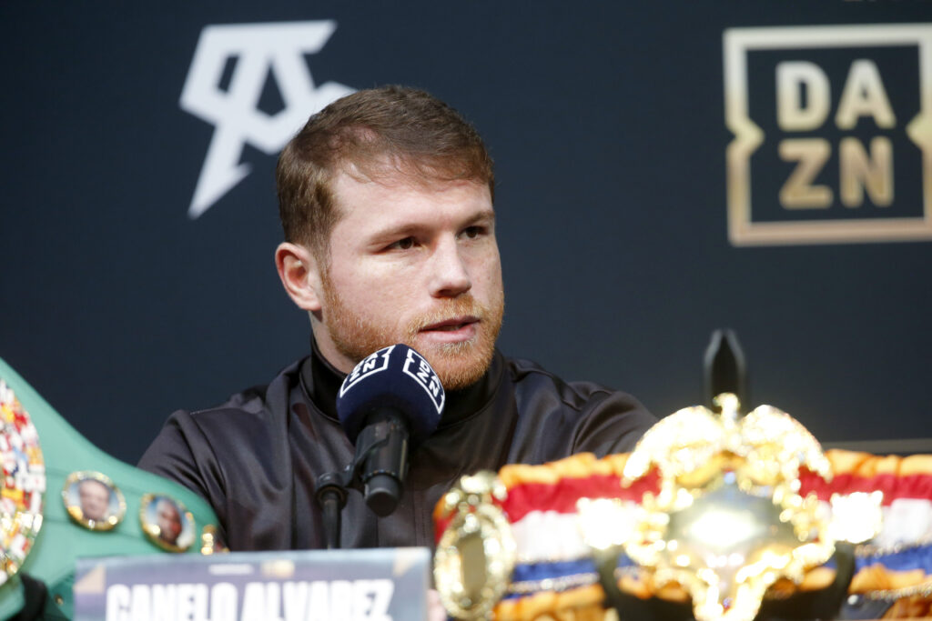 Canelo Alvarez speaking at press conference with belts in foreground